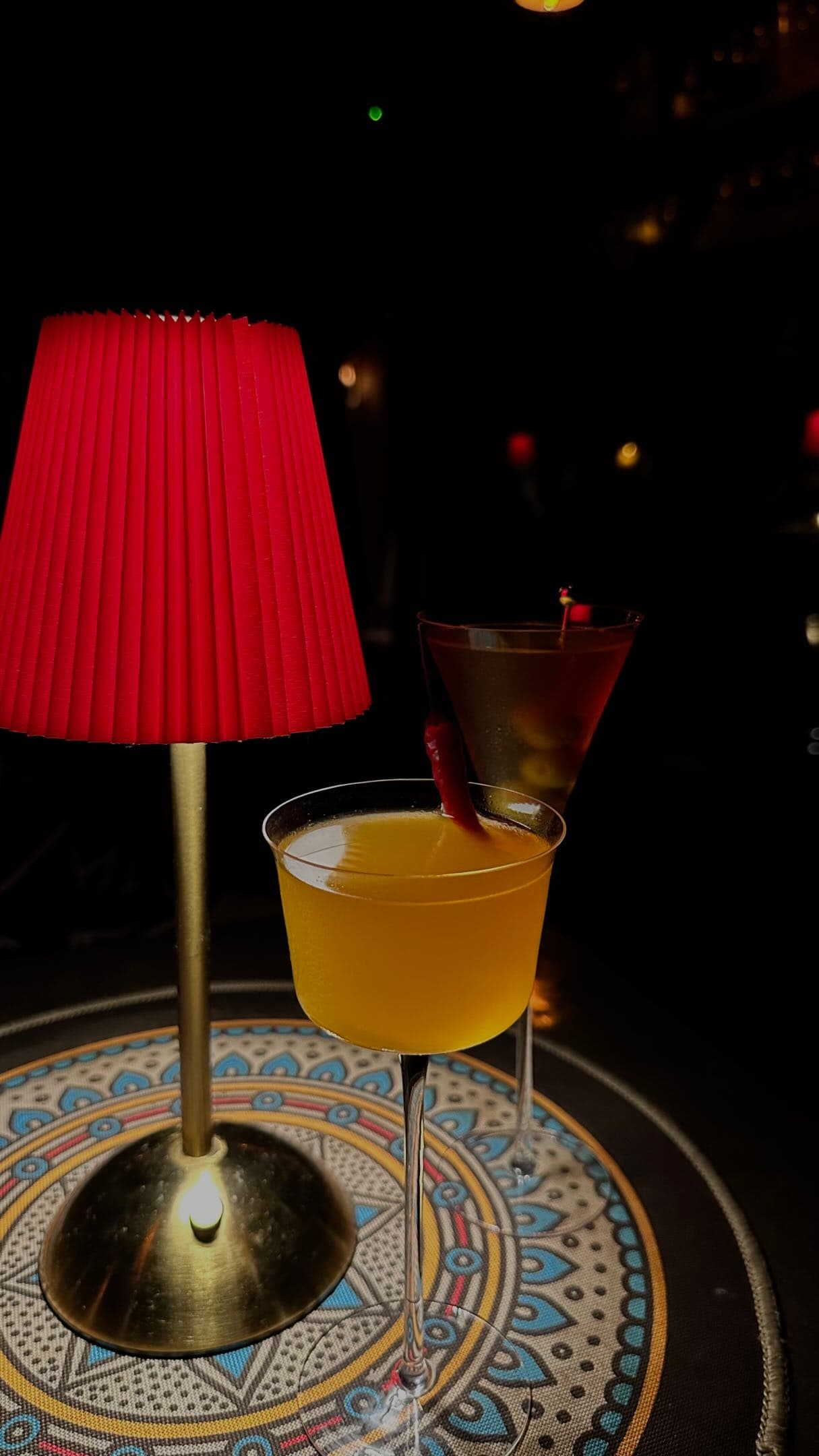Two cocktails beside a glowing red table lamp at Oriental Elixir